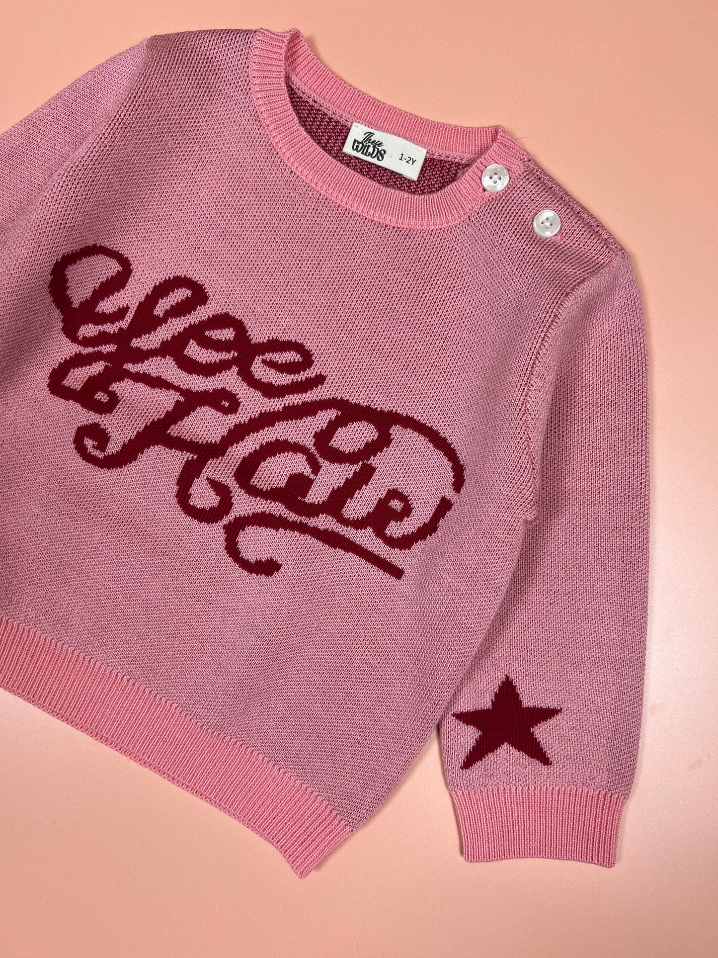 Pink knitted kids’ merino wool sweater with western-themed yeehaw graphic.