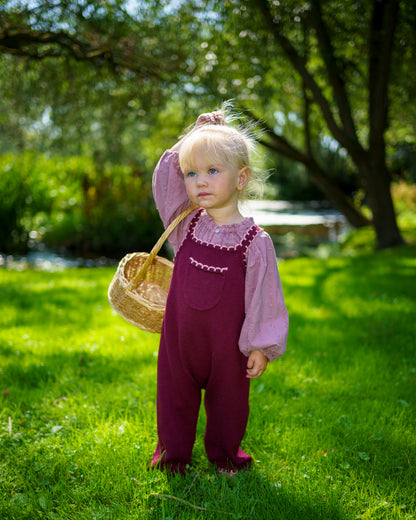 Children’s plum merino wool dungarees with adjustable straps and pink scallop detail