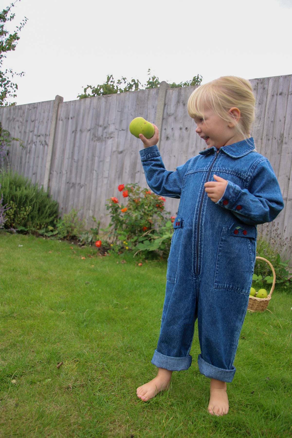 Toddler girl vintage wash denim boiler suit with embroidered cherries and front zip closure, styled for a 1-5 year old toddler jumpsuit outfit.
